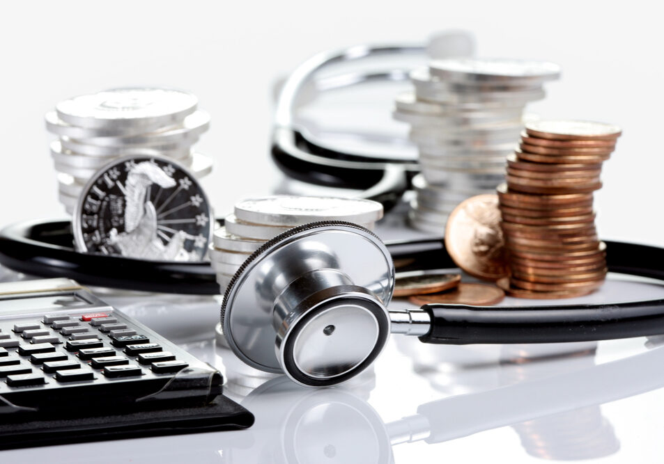 Financial health concept, stethoscope weaving around stacks of silver and gold coins and calculator